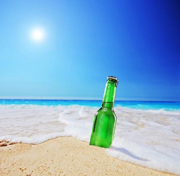 Bierflesje op zandstrand — Stockfoto