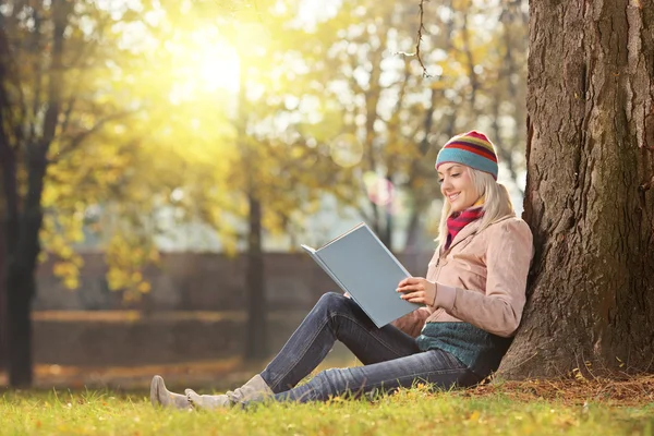 Kobieta w kapeluszu, czytanie książki w parku — Zdjęcie stockowe