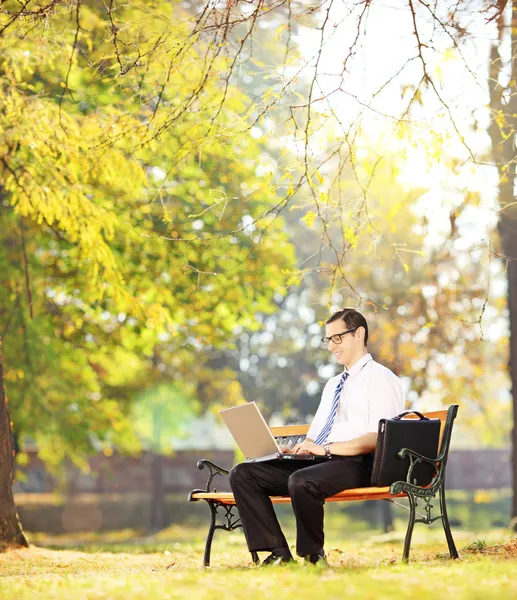 Geschäftsmann sitzt auf Bank und arbeitet am Laptop — Stockfoto