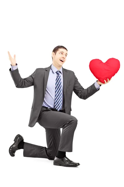 Muž v obleku klečí se srdcem — Stock fotografie