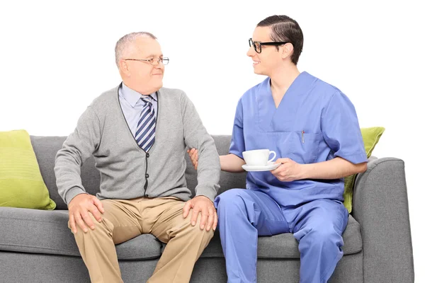 Nurse holding cup of tea for gentleman — Stock Photo, Image