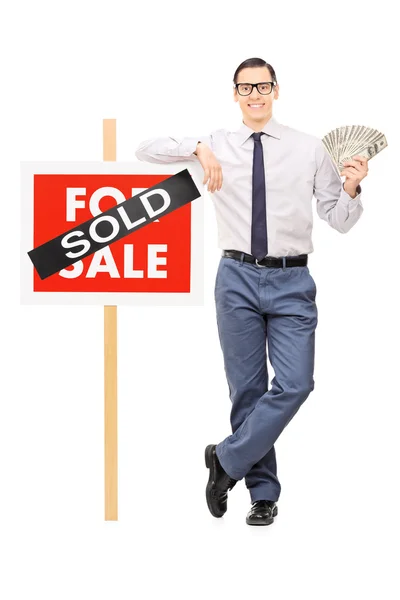 Realtor holding money next to sold sign — Stock Photo, Image