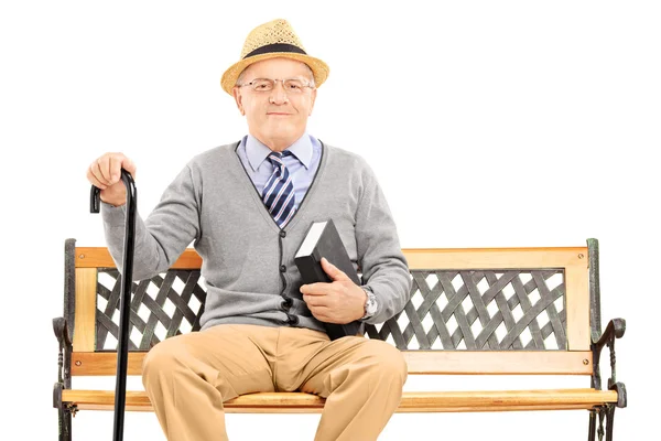 Senior sitzt mit Buch auf Bank — Stockfoto
