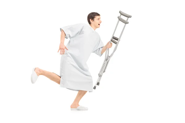 Male patient running holding crutch — Stock Photo, Image