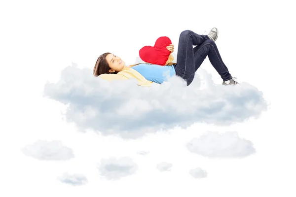 Girl with heart lying on clouds Stock Picture