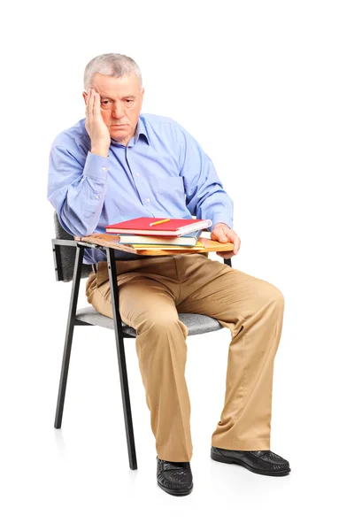 Homme réfléchi assis sur une chaise de classe — Photo