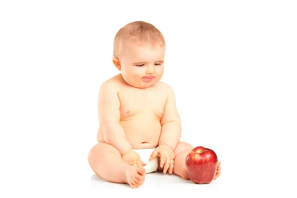Baby boy sitting and looking at an apple — Stock Photo, Image