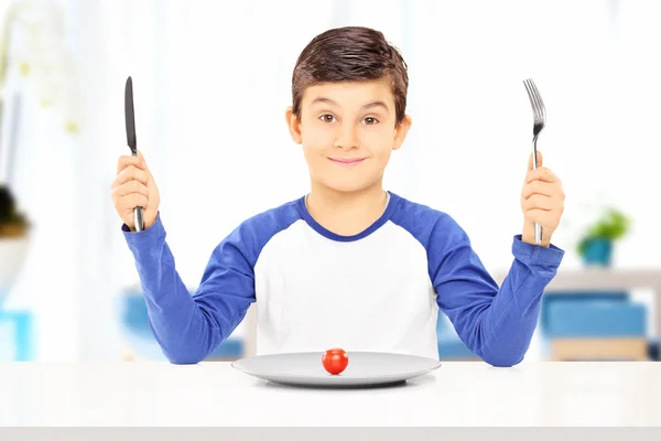 Niño sosteniendo tenedor, cuchillo con tomate — Foto de Stock