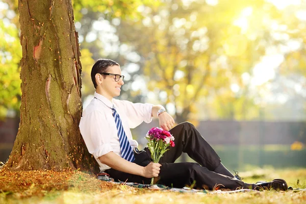 Homem com um monte de flores na grama — Fotografia de Stock