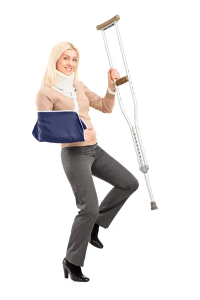 Female with broken arm holding crutch — Stock Photo, Image