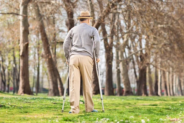 Hombre con muletas caminando —  Fotos de Stock