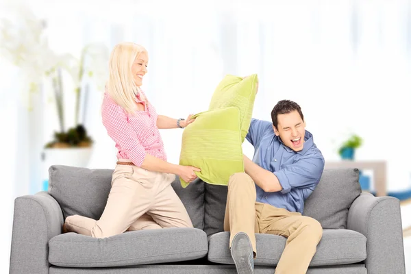 Casal lutando com travesseiros em casa — Fotografia de Stock