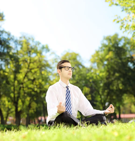 Empresário meditando em uma grama — Fotografia de Stock