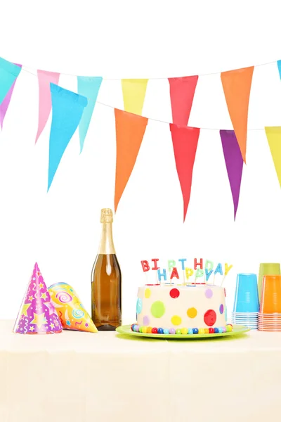 Bottle, party hats and birthday cake — Stock Photo, Image