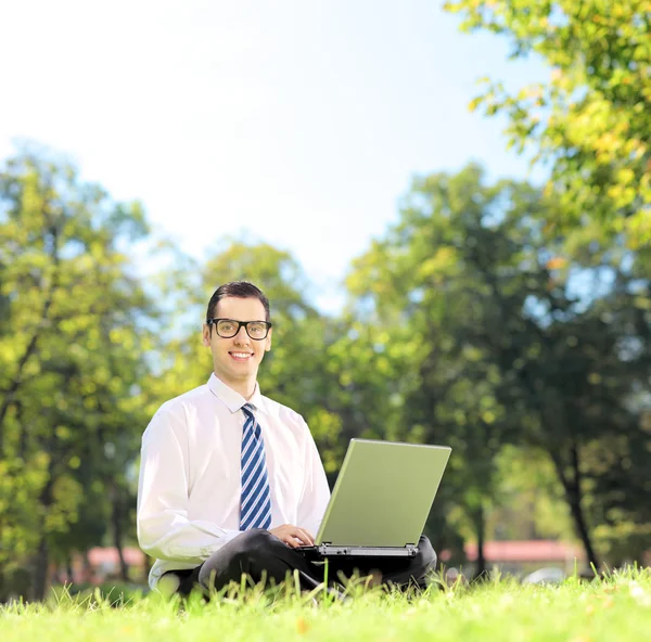 Zakenman op gras die op laptop werkt — Stockfoto