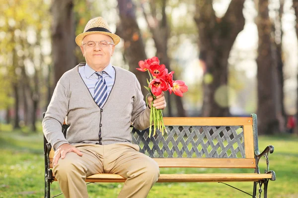Anciano caballero sosteniendo tulipanes — Foto de Stock