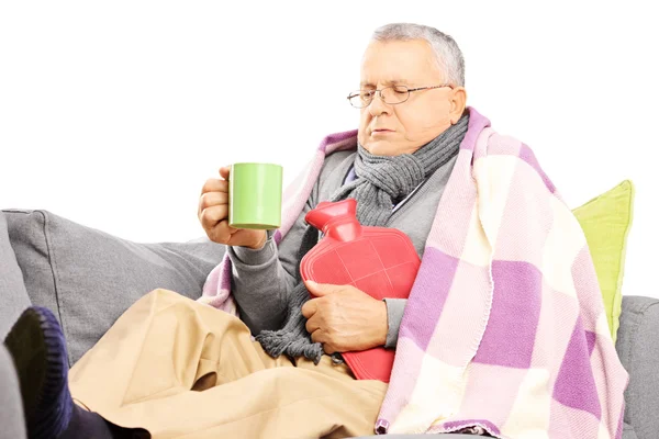 Нездоровый человек на диване пьет горячий чай — стоковое фото