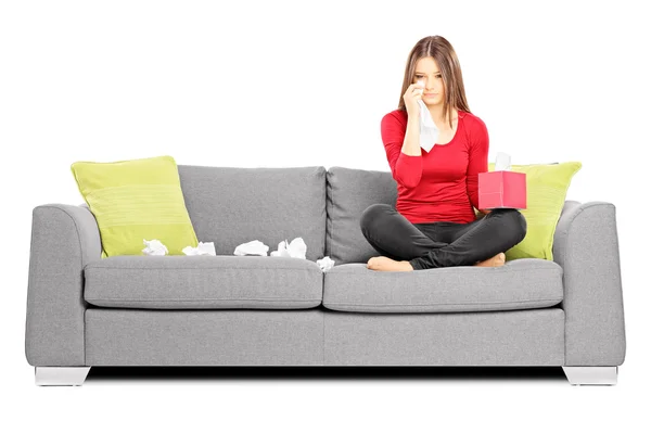 Sad woman on sofa wiping eyes — Stock Photo, Image