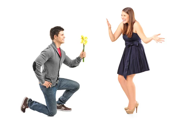 Male kneeling with flowers and girlfriend — Stock Photo, Image