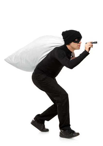 Thief carrying bag and holding torch — Stock Photo, Image