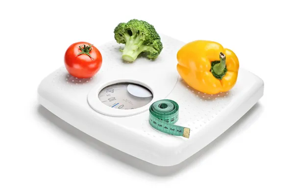Vegetables and measuring tape on scale — Stock Photo, Image