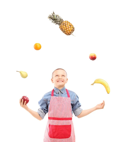 A boy with apron juggling with fruits — Stock Photo, Image