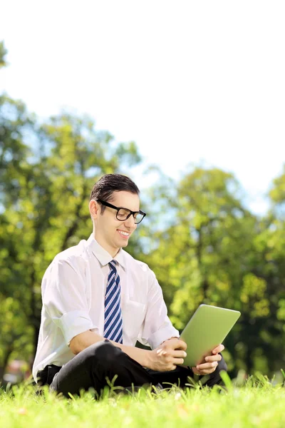 Homme d'affaires sur une herbe travaillant sur une tablette — Photo