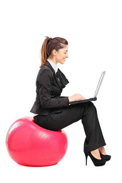 Wanita sibuk yang duduk di atas bola pilates dan mengerjakan komputer notebook — Stok Foto