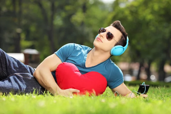 Mężczyzna leżąc na trawie z czerwonym sercem — Zdjęcie stockowe