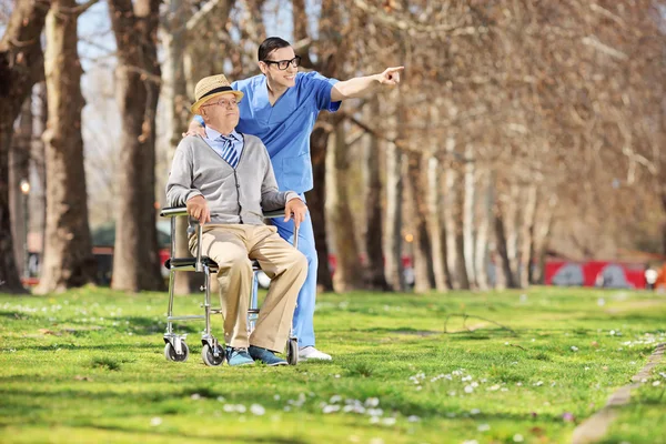 Enfermera mostrando algo al hombre en silla de ruedas — Foto de Stock