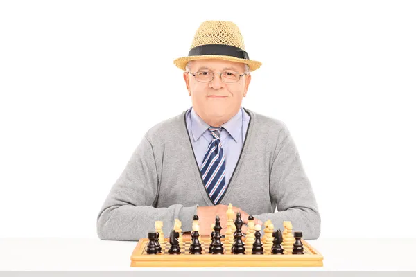 Pensionista posando detrás del tablero de ajedrez — Foto de Stock