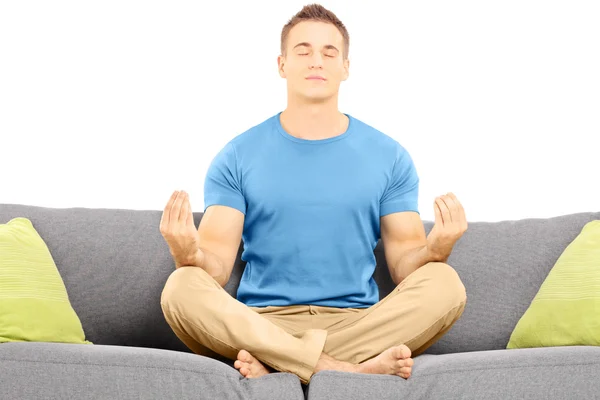 Guy meditating seated on sofa — Stock Photo, Image