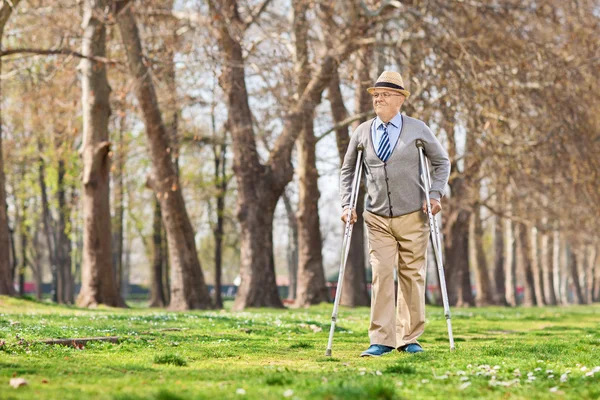 Senior gentleman walking with crutches — Stock Photo, Image
