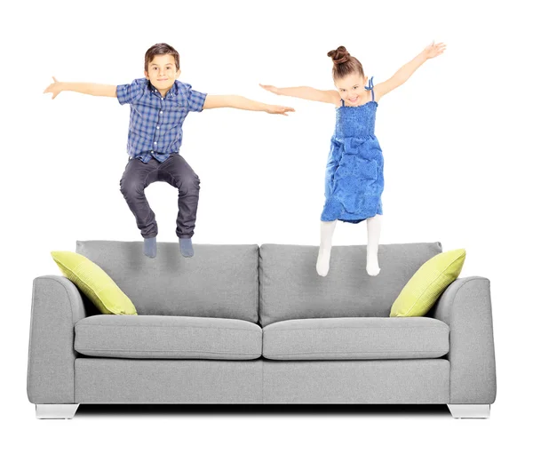 Brother and sister jumping on sofa — Stock Photo, Image