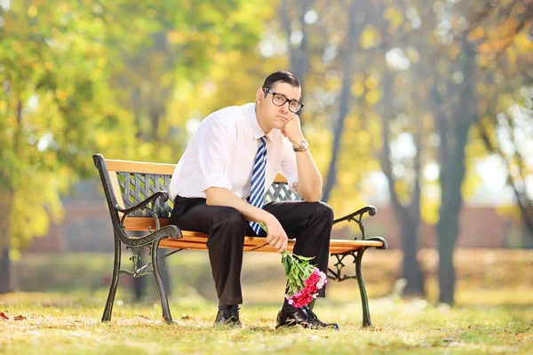 Triste cara segurando um buquê de flores — Fotografia de Stock