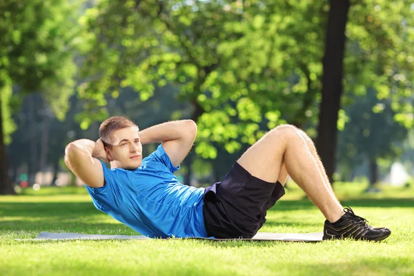 Sportler trainiert Bauchmuskeln im Park — Stockfoto