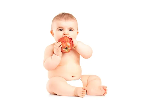 A 9 months old baby boy sitting and eating an apple — Stock Photo, Image