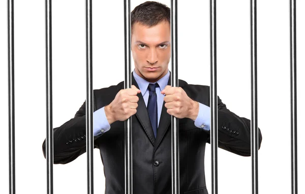 A businessman in jail holding bars — Stock Photo, Image