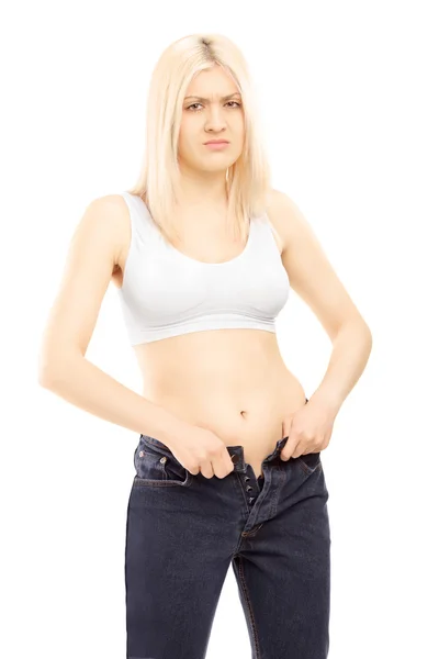 Woman trying to put on old jeans — Stock Photo, Image