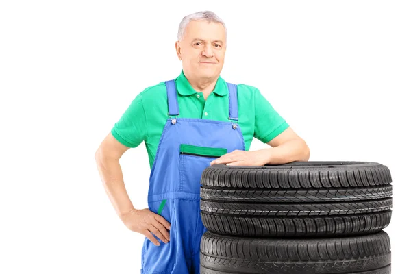Trabajador posando sobre neumáticos de coche — Foto de Stock