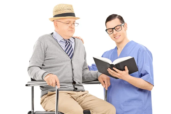 Male nurse reading to an elderly gentleman — Stock Photo, Image