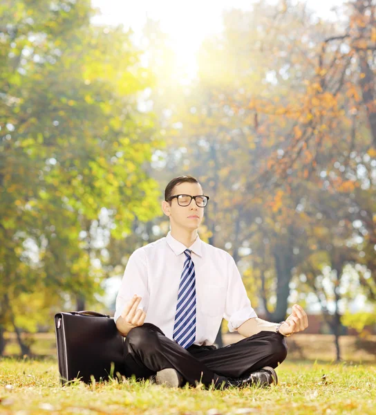 Empresário meditando em uma grama — Fotografia de Stock