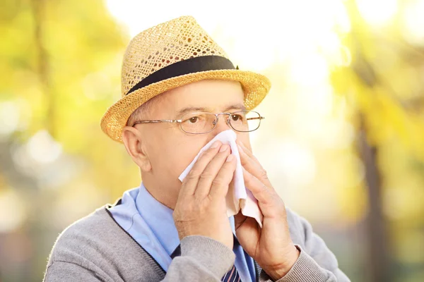 Mature man blowing his nose — Stock Photo, Image