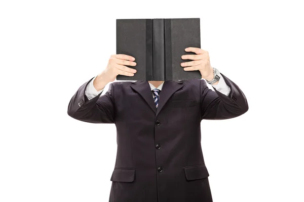 Geschäftsmann hält sich ein Buch vor das Gesicht — Stockfoto