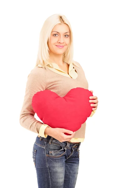 Blond girl holding a heart-shaped pillow Stock Photo