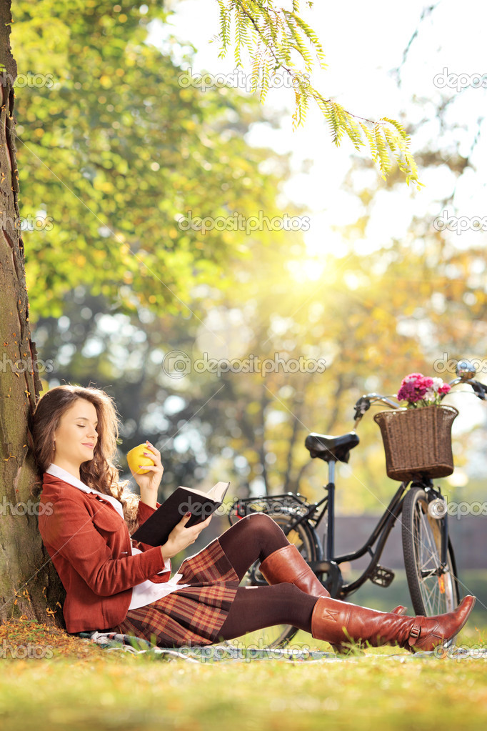 Female reading book and eating apple