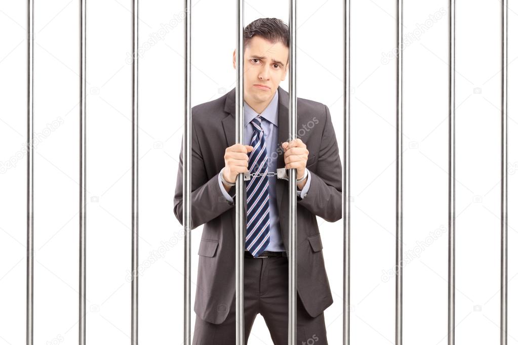 Sad handcuffed businessman in jail