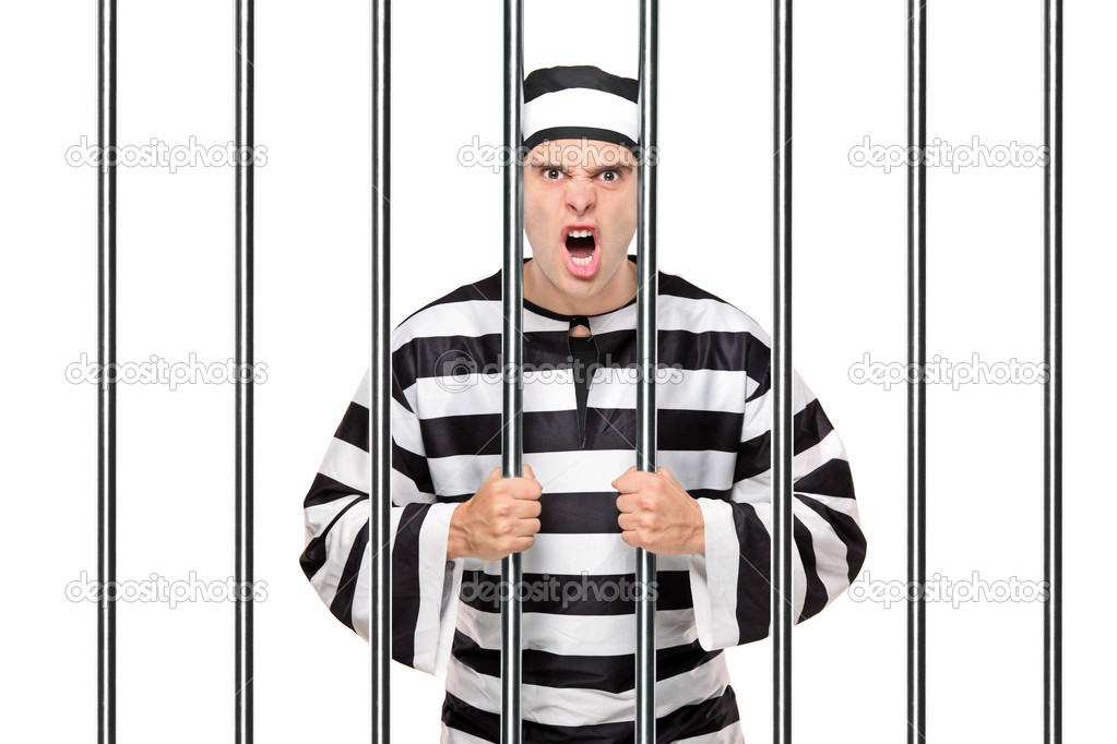 Angry prisoner standing behind bars