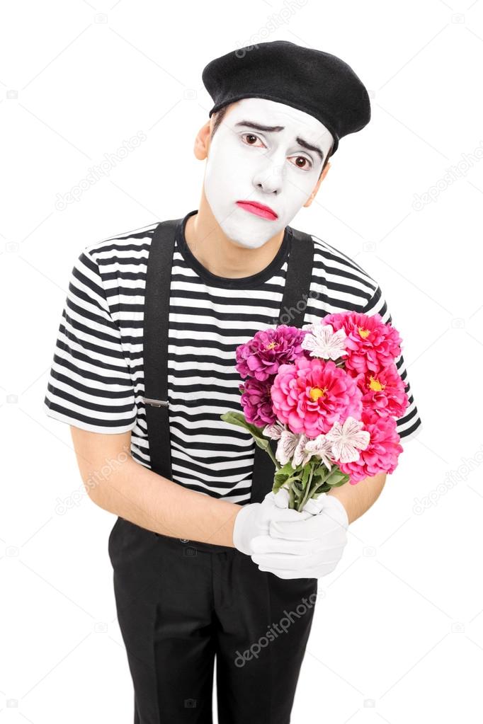 Sad mime artist holding bouquet