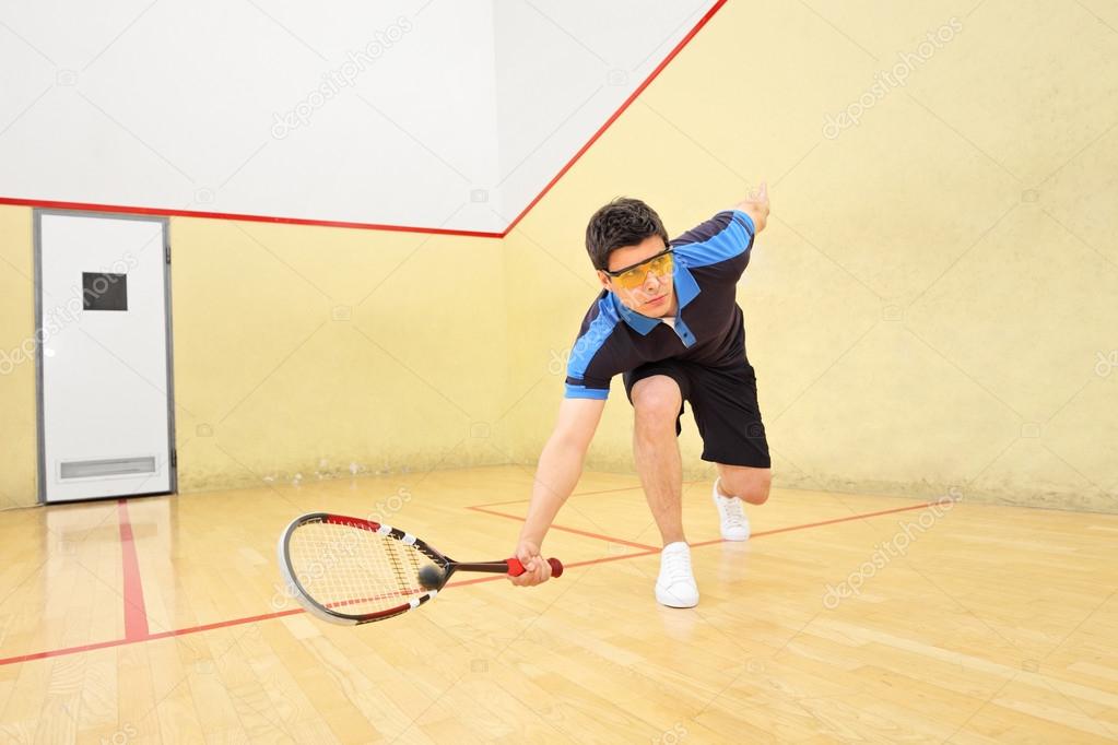 Squash player hiting ball